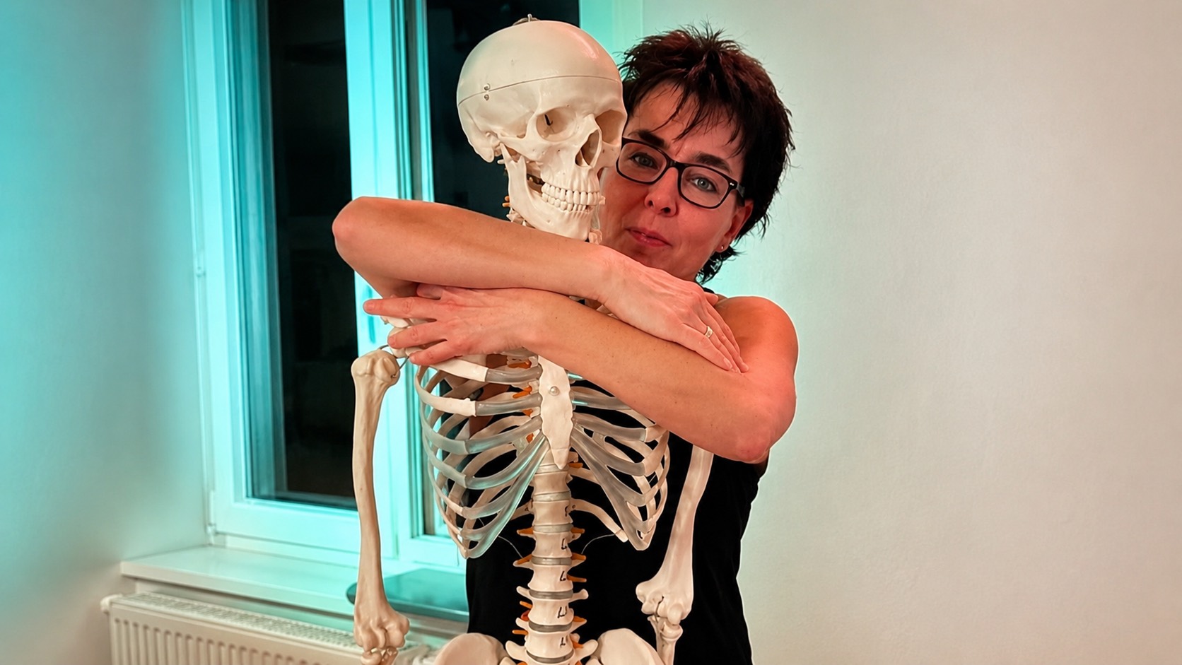 Trainerin mit Anatomie-Modell bei Body & Care